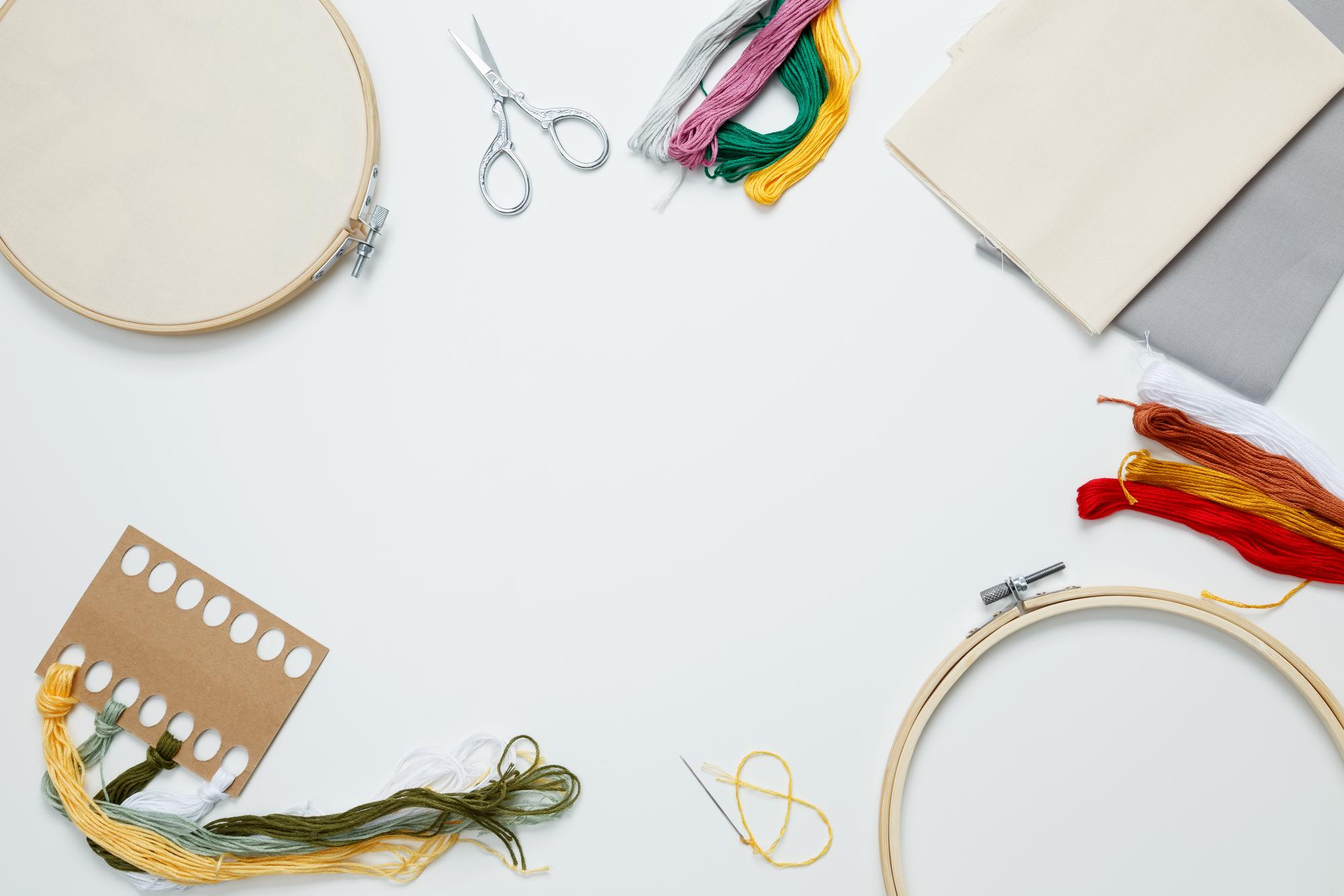 Tavolo da lavoro con fili colorati, telaio e strumenti per ricamo